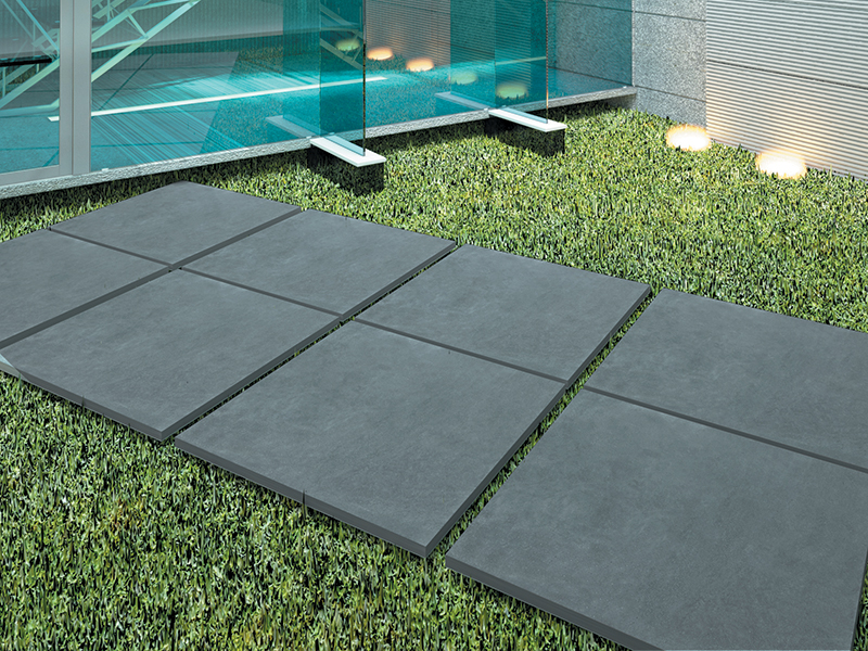 Phối cảnh các tấm Q-Stone xám đậm đặt thành lối đi xen cỏ.